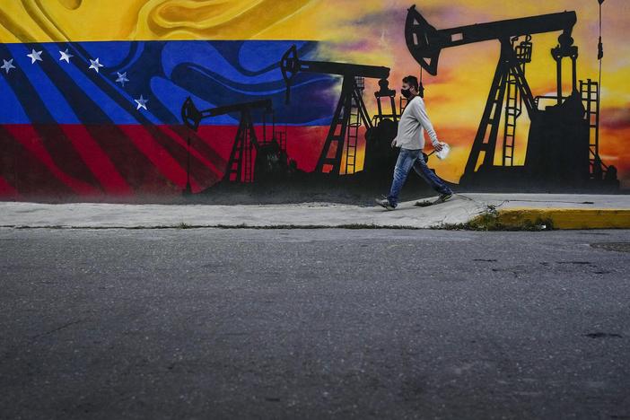 A man walks past a mural featuring oil pumps and wells in Caracas, Venezuela, as the country faces the prospect of the U.S. reimposing oil sanctions.