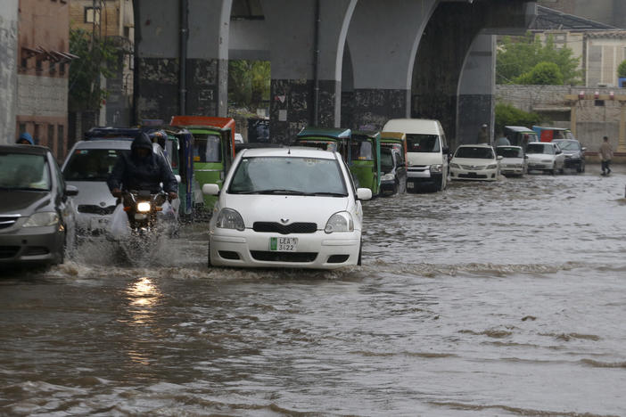 A motorcyclist and car drivers drive through a flooded road caused by heavy rain in Peshawar, Pakistan, Monday, April 15, 2024.