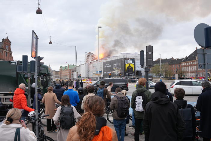 People watch as fire and smoke rise out of the Old Stock Exchange in Copenhagen.