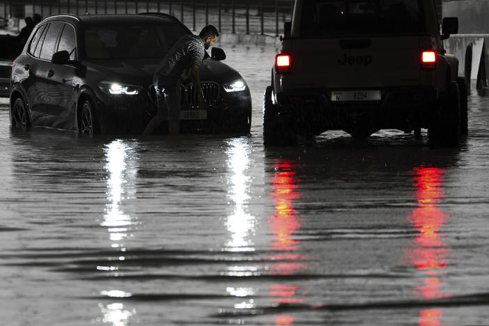 A man tries to work on his stalled SUV in standing water in Dubai, United Arab Emirates, on Tuesday.