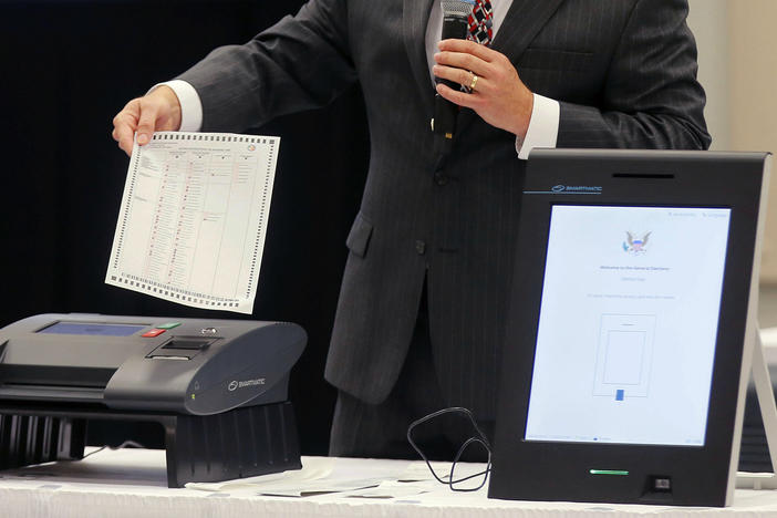 A Smartmatic representative demonstrates his company's system, which has scanners and touch screens with printout options, at a meeting of the Secure, Accessible & Fair Elections Commission, on Aug. 30, 2018, in Grovetown, Ga.