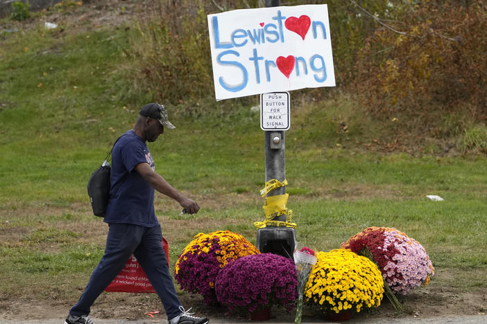 A man walks by flowers and a sign of support for the community, Oct. 28, 2023, in the wake of the mass shootings that occurred on in Lewiston, Maine. The Maine Legislature on Thursday approved sweeping gun safety legislation nearly six months after the deadliest shooting in state history.