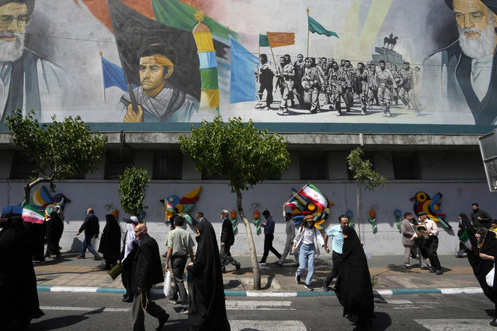 Iranian worshippers walk past a mural showing the late revolutionary founder Ayatollah Khomeini, right, Supreme Leader Ayatollah Ali Khamenei, left, and Basij paramilitary force, in an anti-Israeli gathering after their Friday prayer in Tehran, Iran, on Friday.