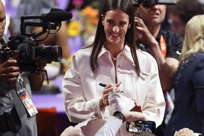 Caitlin Clark, pictured autographing sneakers before the WNBA draft last Monday, is helping drive demand for the league's ticket sales and TV coverage.