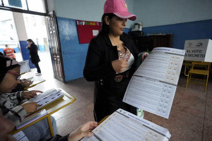 A woman holds the ballot to vote in a referendum proposed by President Daniel Noboa to endorse new security measures aimed at cracking down on criminal gangs fueling escalating violence, in Quito, Ecuador, Sunday, April 21, 2024.