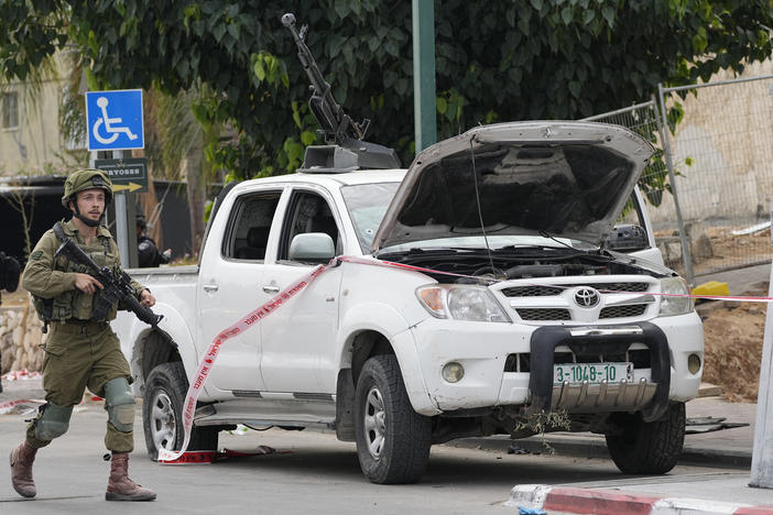 Israeli soldier walks by a pickup truck used by Palestinian militants in Sderot, Israel, on Saturday, Oct. 7, 2023.