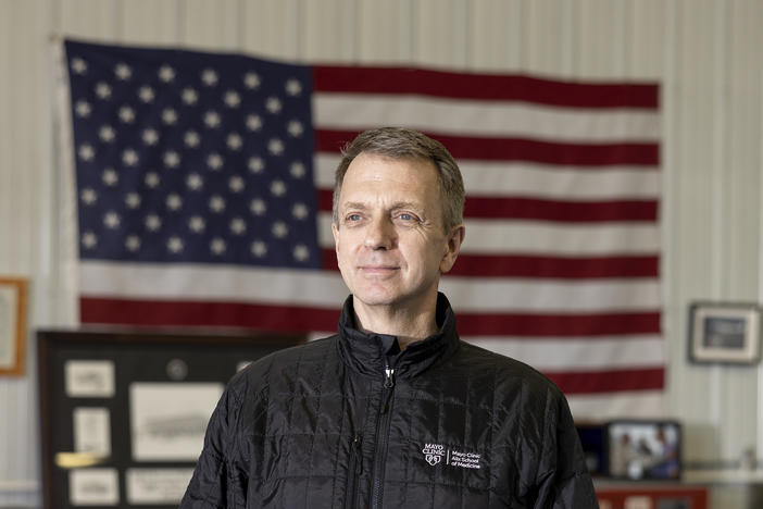 Dr. Todd Rasmussen stands in his home office in Rochester, Minn. He is a former combat surgeon who did six tours in Iraq and Afghanistan.