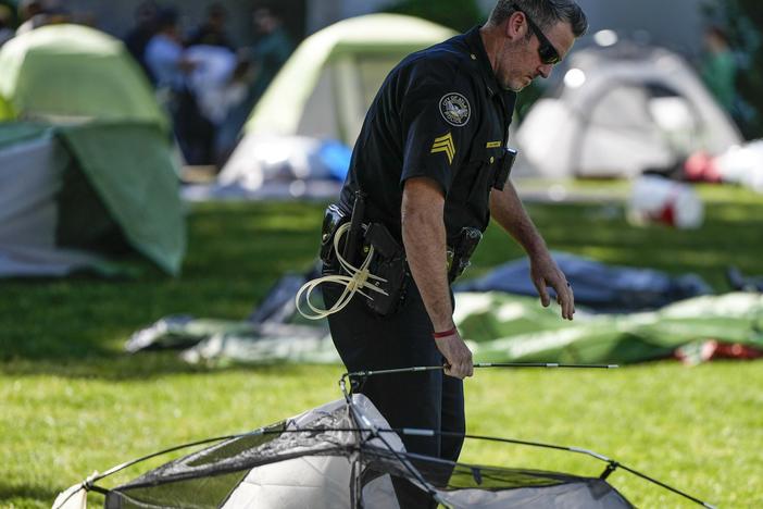 An Atlanta police officer takes down tents on the campus of Emory University after a pro-Palestinian demonstration Thursday in Atlanta.