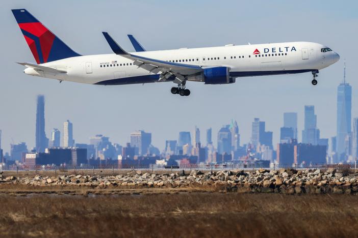 A Boeing 767 passenger aircraft of Delta Air Lines arrives from Dublin at JFK International Airport in New York as the Manhattan skyline looms in the background on Feb. 7, 2024.