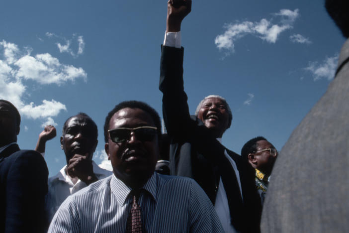 Bodyguards keep close watch as Nelson Mandela celebrates his victory in the South African presidential elections of 1994. As the head of the African National Congress, he helped to build the country's new multiracial government and to establish the free elections in which he won his presidency.