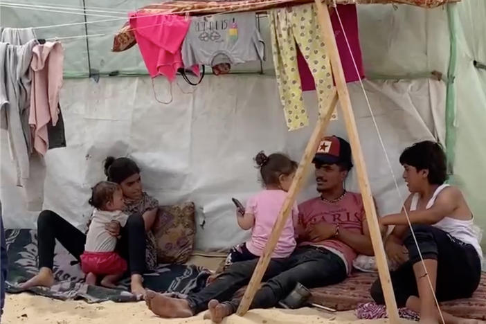 Displaced Palestinians in Rafah sit in the shade of their tent on a 100-degree day in the Gaza Strip.