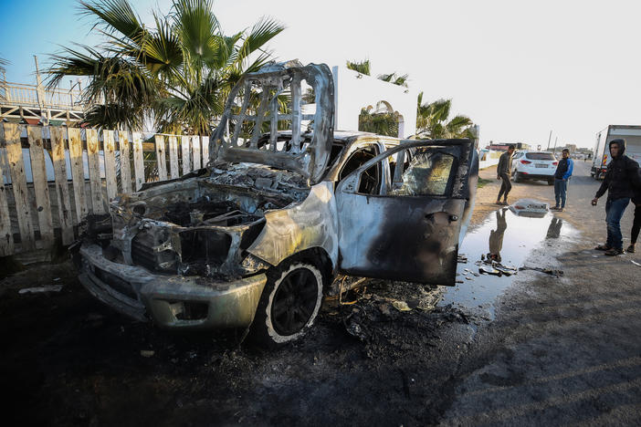People stand next to a vehicle in Deir Al-Balah, in the central Gaza Strip, on April 2, where workers from the World Central Kitchen (WCK), were killed in Israeli airstrikes, according to the NGO.