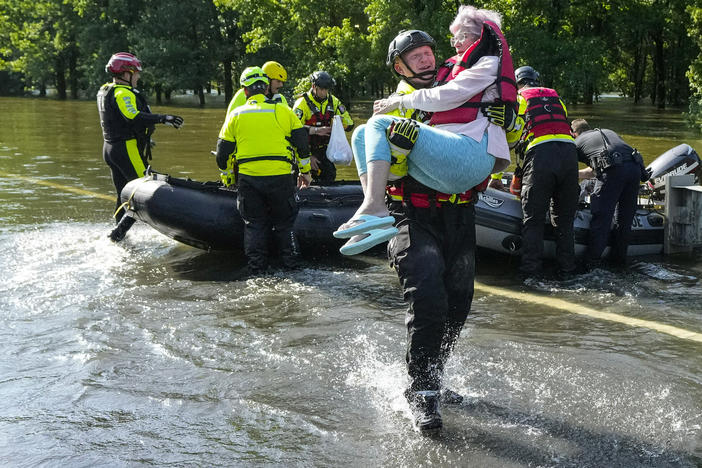 Conroe firefighter Cody Leroy carries a resident evacuated in a boat by the CFD Rapid Intervention Team from her flooded home in the aftermath of a severe storm on Thursday in Conroe, Texas.