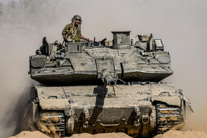 Israeli soldiers drive a tank at a staging ground near the border with the Gaza Strip, in southern Israel on Sunday.