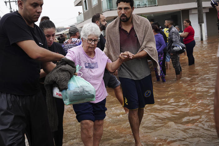 Residents evacuate from a neighborhood flooded by heavy rains, in Canoas, Rio Grande do Sul state, Brazil, Saturday, May 4, 2024.