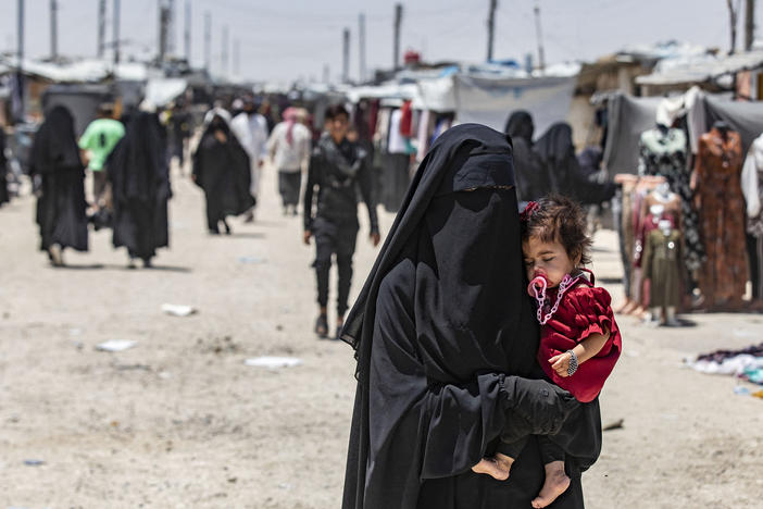 A woman carries a child as she walks through the al-Hol refugee camp in northeastern Syria in October 2023.