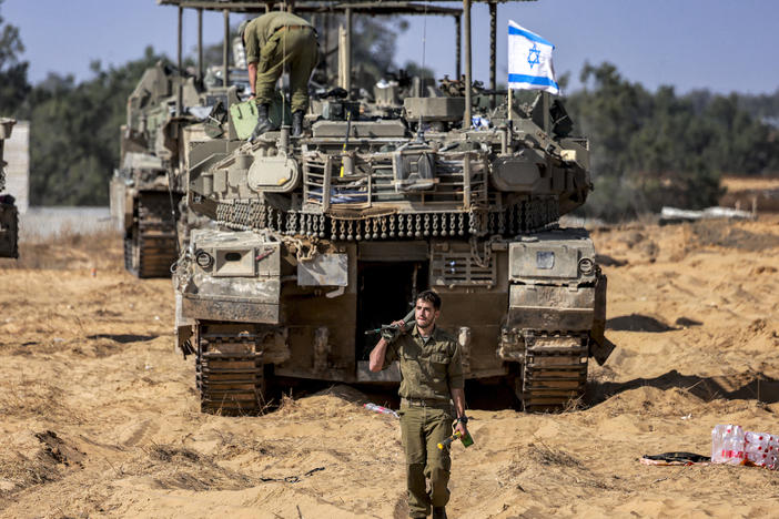 An Israeli army soldier walks past a main battle tank stationed at a position near the border with the Gaza Strip in southern Israel on April 30.