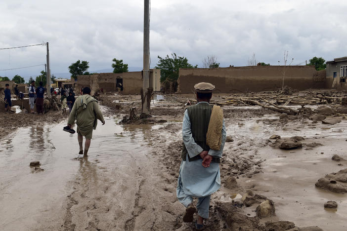 People are seen near to their damaged homes after heavy flooding in Baghlan province in northern Afghanistan on Saturday.
