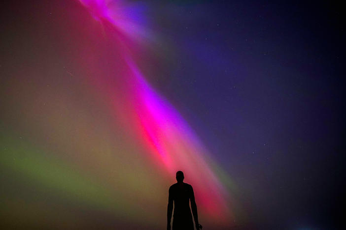 Crosby Beach, Liverpool, England: The aurora borealis, also known as the northern lights, glow on the horizon at Another Place by Anthony Gormley.