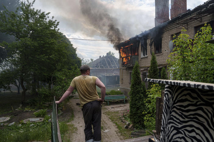 A local resident looks at a neighbour's house on fire after a Russian airstrike in Vovchansk, Ukraine, on Saturday, May 11, 2024.