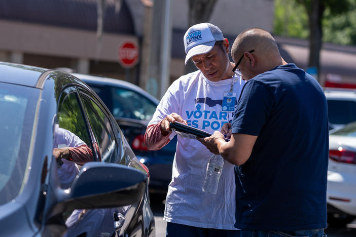 Poder Latinx canvasser Humberto Orjuela helps Andres Navarro register to vote in a Presidente Supermarket parking lot in Orlando on April 20. New restrictions in Florida have made voter registration work more difficult for Poder Latinx and other third-party groups.