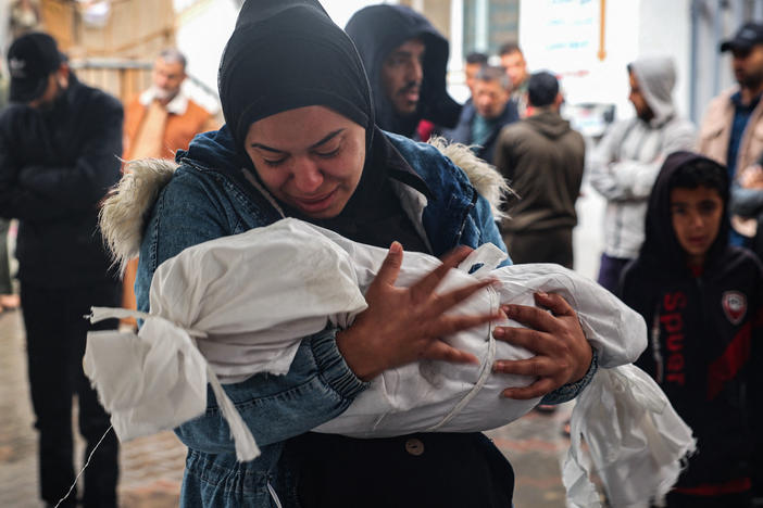 A woman mourns as she carries the shrouded body of a child killed following overnight Israeli strikes on Rafah in the southern Gaza Strip, on May 6.