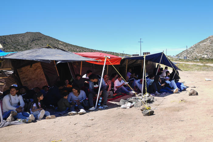 A group of people wait to be processed after crossing the border between Mexico and the United States as they seek asylum in April 2024, near Jacumba, Calif.