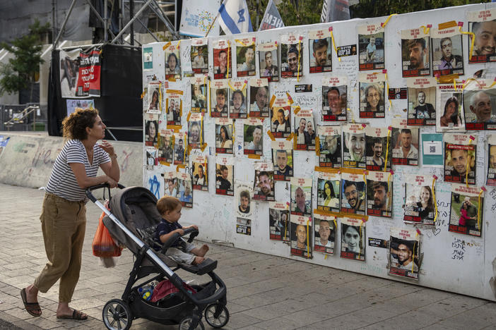Passersby observe the photos of hostages held in the Gaza Strip that are plastered to the walls of a plaza known as Hostages Square in Tel Aviv, Israel, Friday, May 17, 2024.