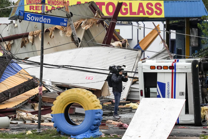 A video photojournalist shoots footage of damage at a tire shop at the intersection of Sowden and Bingle in the aftermath of a severe storm on Friday, in Houston.