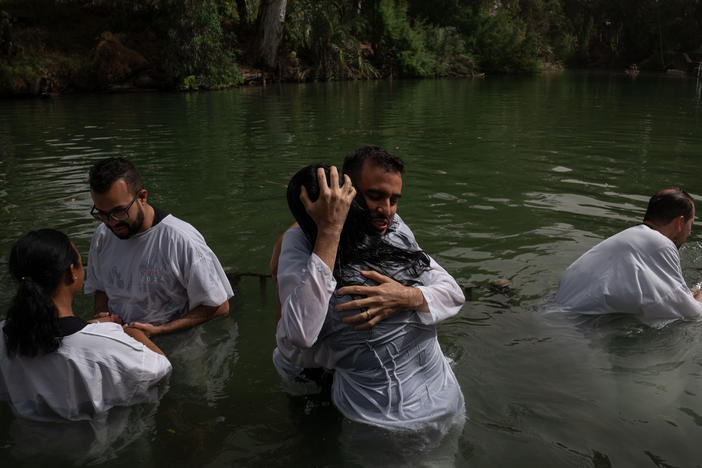 Evangelicals from Brazil wade, pray and get baptized in the Jordan river in Israel.