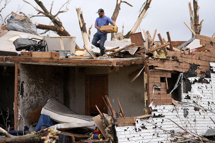 A man sorts through the remains of a home damaged by a tornado on Tuesday in Greenfield, Iowa.