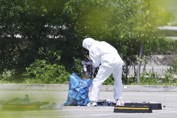 An officer wearing protective gear collects the trash from a balloon presumably sent by North Korea, in Siheung, South Korea, on Sunday.