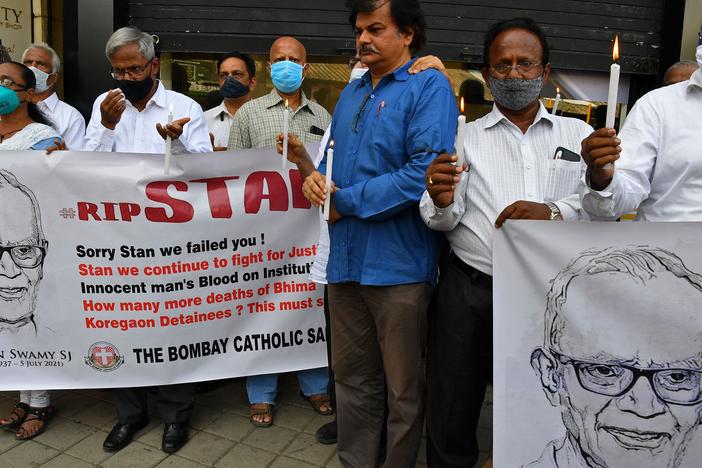 People hold posters and candles outside a Mumbai church holding a memorial mass for the Indian rights activist and Jesuit priest Stan Swamy on July 6, 2021. Swamy was detained for nine months without trial under Indian anti-terrorism laws, and died on July 5, 2021 ahead of a bail hearing, officials said.