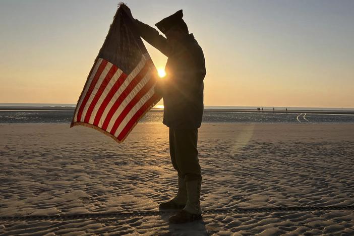 Christophe Receveur, of France, unfurls an American flag he bought six months ago in Gettysburg, Pa., to mark D-Day on Thursday on Utah Beach, Normandy. 