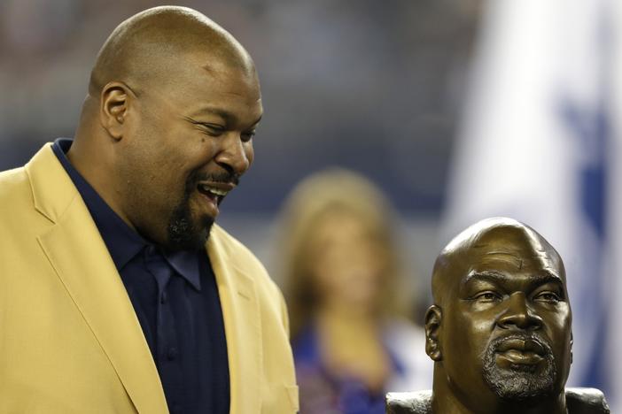 Former Dallas Cowboys player and Hall of Fame player Larry Allen looks down at a bust of himself as Allen is honored at halftime of an NFL football game against Washington on Oct. 13, 2013, in Arlington, Texas. 