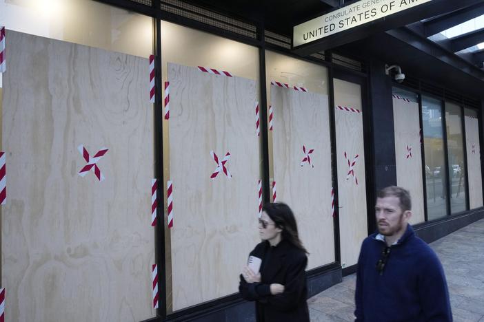 A couple walks past the boarded windows at the U.S. consulate as police investigate the vandalism in Sydney on Monday.