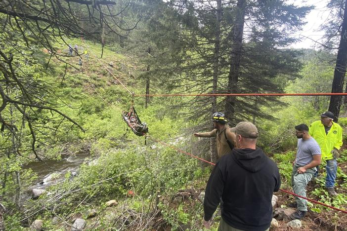 In this image provided by the Baker County Sheriff's Office, responders aid in rescue efforts after a vehicle went into an embankment on U.S. Forest Service Road 39 on June 3, 2024, in Oregon. A dog helped his owner get rescued after the crash by traveling nearly four miles to the campsite where the man was staying with family, which alerted them that something was wrong, authorities said.  