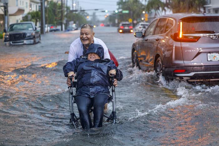 Victor Corone, 66, pushes his wife Maria Diaz, 64, in a wheelchair through more than a foot of floodwater in Miami Beach, Fla., on Wednesday, June 12, 2024. The annual rainy season has arrived with a wallop in much of Florida.