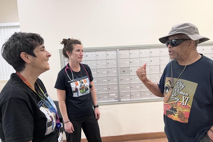 Nurses Lisa Stambolis and Ashley Gresh of the Neighborhood Nursing team talk with Percy Jones. Members of the nursing team visit his apartment building weekly, and Jones credits them with easing his worries about recovering from a hernia surgery when he couldn't get a timely appointment with his doctor. 