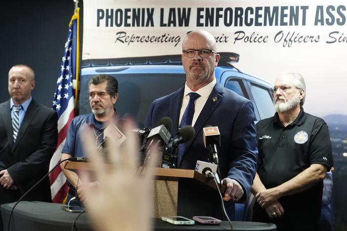 Darrell Kriplean, president of the Phoenix Law Enforcement Association, which represents about 2,200 Phoenix officers, stands at a lectern with microphones to take a question during a news conference Thursday in Phoenix. A Justice Department report said Phoenix police discriminate against Black, Hispanic and Native American people, unlawfully detain homeless people and use excessive force, including unjustified deadly force.