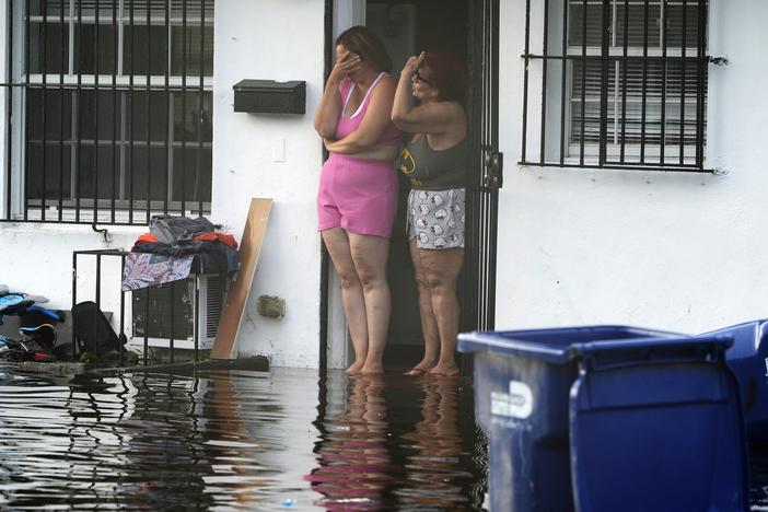 Two women react as they see flooding on their street on Thursday, June 13, 2024, in North Miami, Fla.