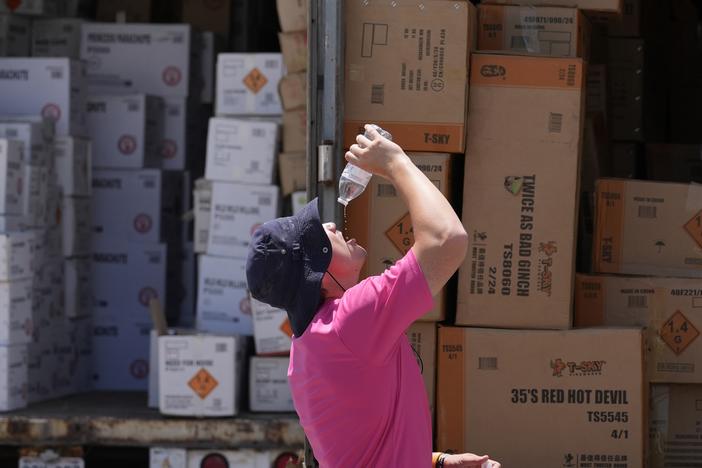 Wyatt Seymore pours the last drops of liquid from a water bottle into his mouth on June 17 as he takes a break from unloading a stiflingly hot trailer of fireworks outside Powder Monkey Fireworks ahead of the opening of the stand in Weldon Spring, Mo. 