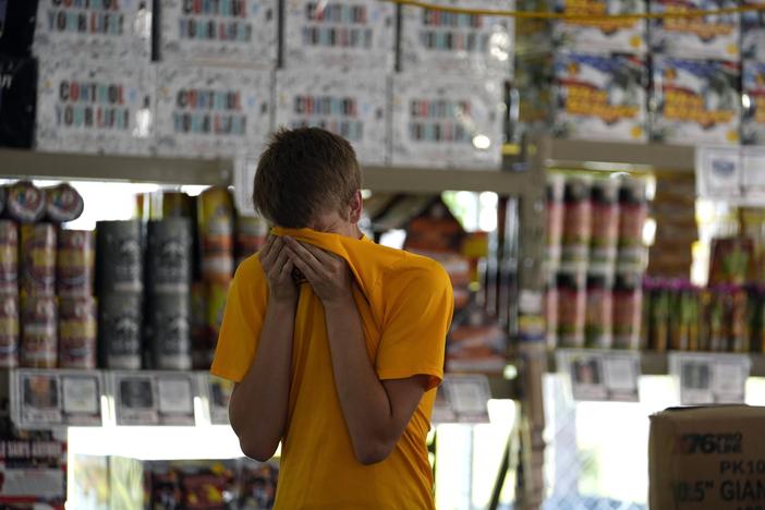 Hunter Van Dyne pauses to wipe sweat from his forehead inside a hot fireworks tent as he works to set up for the opening of Powder Monkey Fireworks, in Weldon Spring, Mo., on Monday.