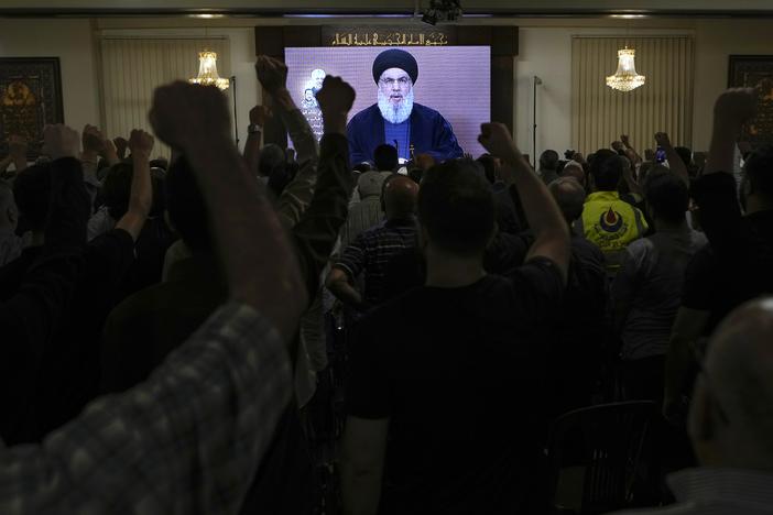 Hezbollah supporters raise their fists and cheer as they watch a speech given by Hezbollah leader Hassan Nasrallah during a ceremony to commemorate the death of a senior Hezbollah commander in the southern Beirut suburb of Dahiyeh, Lebanon, on Wednesday. 