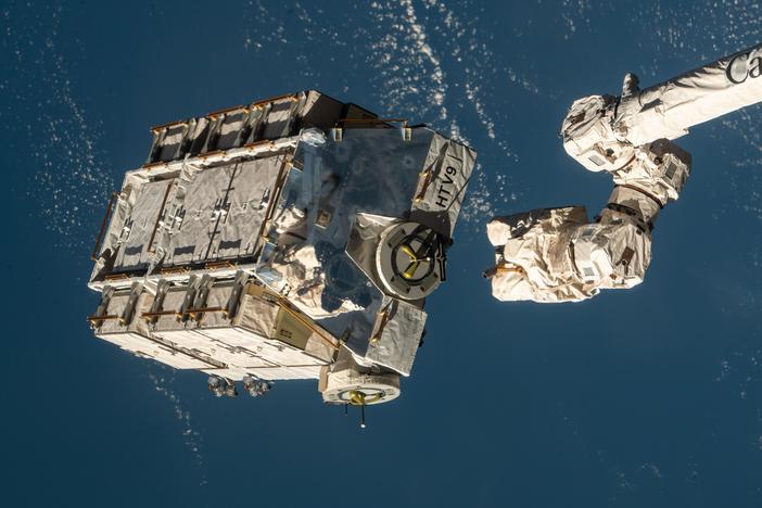 A robotic arm at the International Space Station is seen releasing a pallet packed with batteries in 2021. NASA says a metal alloy stanchion from that flight equipment is what landed in a Florida home.