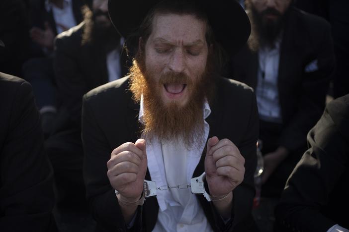 An Ultra-Orthodox Jewish man wears handcuffs as he sits on a street during a protest against army recruitment in Jerusalem on June 2.