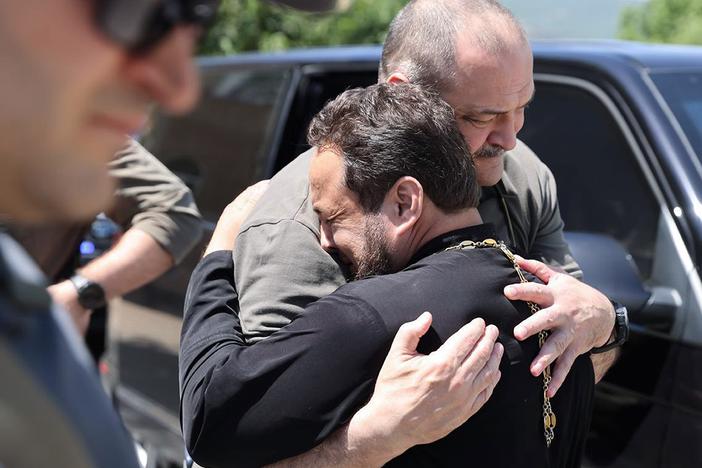 In this photo released by the Telegram channel of the administration of the head of Dagestan Republic of Russia on Monday, the head of Dagestan Republic, Sergei Melikov (center), embraces and comforts a priest as he visits an Orthodox church in Derbent after a counterterrorism operation.