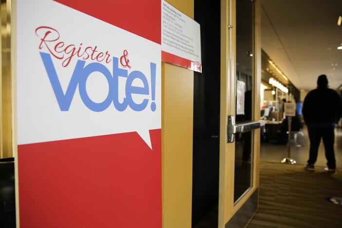 A sign saying “Register & vote!” is on display at the King County elections office in Renton, Wash., in 2020.