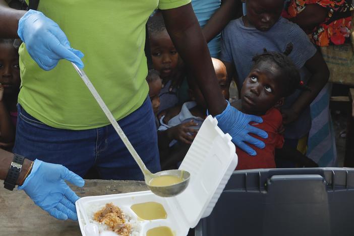 A server ladles soup into a container as children line up to receive food at a shelter for families displaced by gang violence, in Port-au-Prince, Haiti, in March 2024. Gang violence in Haiti has displaced over 300,000 children since March, according to a new report from the U.N. children's agency released late Tuesday.