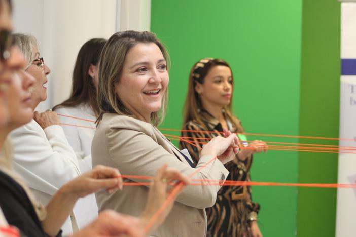 Scarlett Lanzas, second from right, and other information navigators do an exercise in which they use orange string to symbolize how communities are interconnected, at a Nov. 8, 2023, orientation for a pilot project on combating bad information.